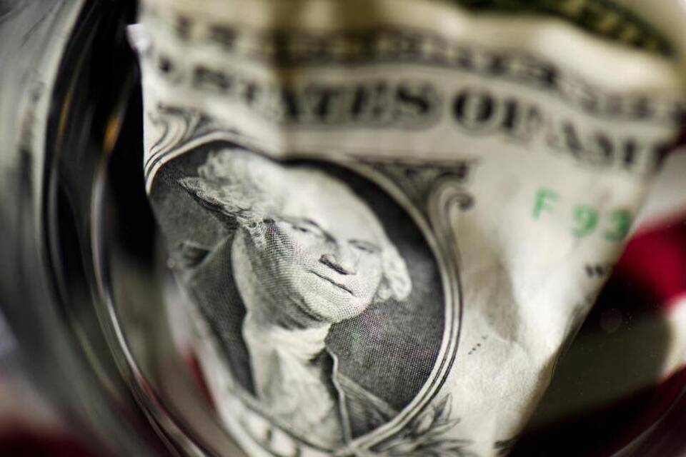 Ein US-Dollar Geldschein liegt in einem Wasserglas