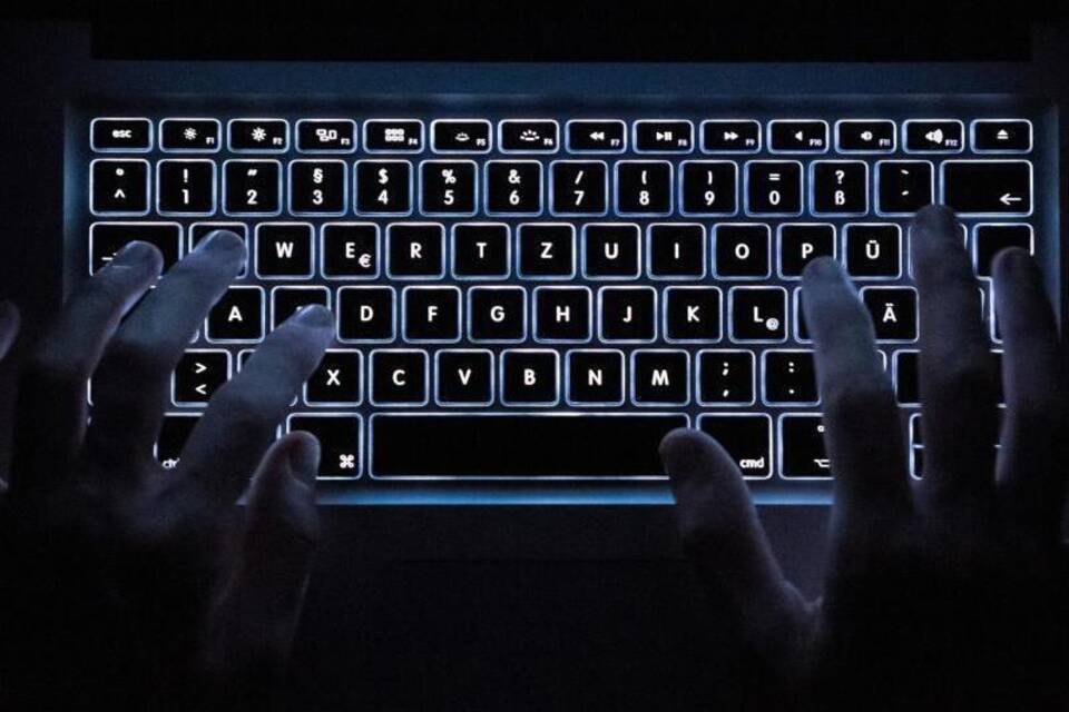 Ein Mann benutzt die beleuchtete Tastatur eines Notebooks Ein Mann benutzt die beleuchtete Tastatur eines Notebooks