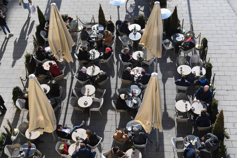 Gäste sitzen vor einem Café in der Sonne