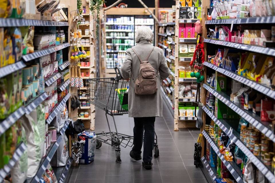 Eine Frau geht mit ihrem Einkaufswagen durch einen Supermarkt