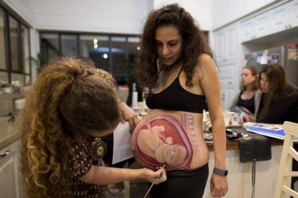 Israelin bemalt Bäuche schwangerer Frauen