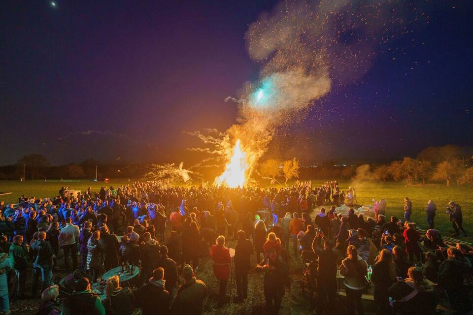 Menschen stehen um ein Osterfeuer