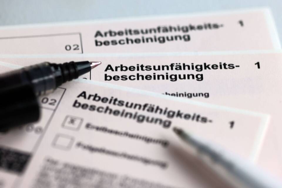 Stifte liegen auf Arbeitsunfähigkeitsbescheinigungen Stifte liegen auf Arbeitsunfähigkeitsbescheinigungen