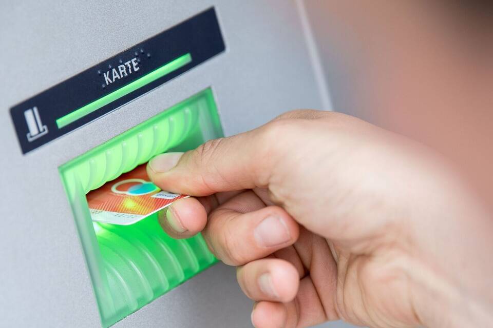 Person steckt Girokarte in einen Geldautomaten