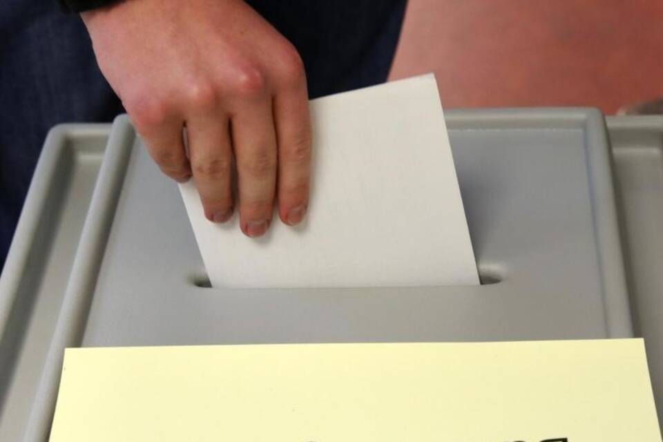Mann wirft Stimmzettel in Urne