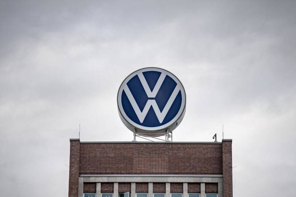 Ein VW-Logo steht auf einem Verwaltungshochhaus