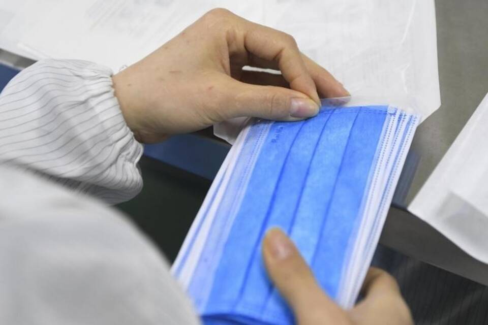 Ein Mitarbeiter verpackt Schutzmasken. Symbolbild Ein Mitarbeiter verpackt Schutzmasken. Symbolbild
